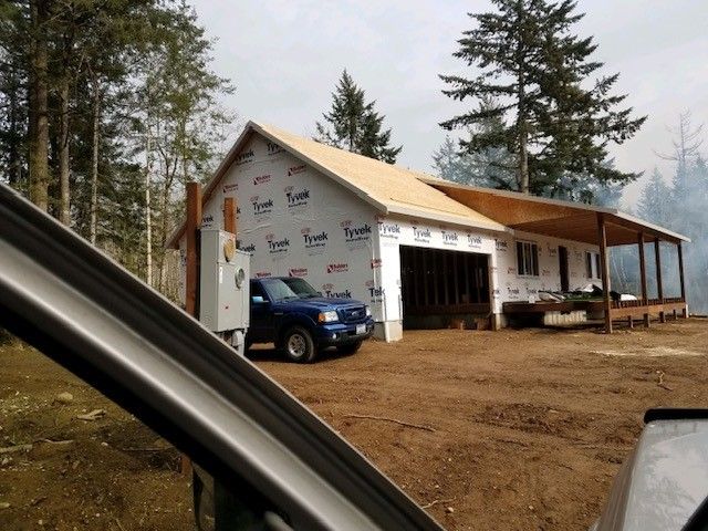 A blue truck is parked in front of a house under construction