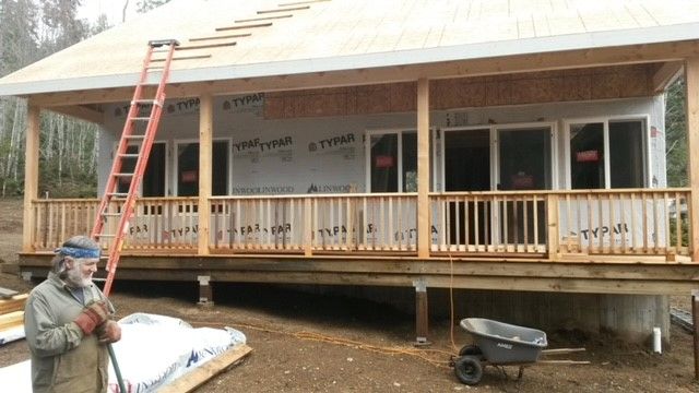 A man is standing in front of a house under construction