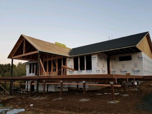 A house is being built on stilts and has a black roof
