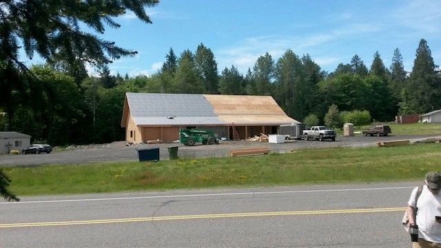 A man is walking down the road in front of a house under construction.