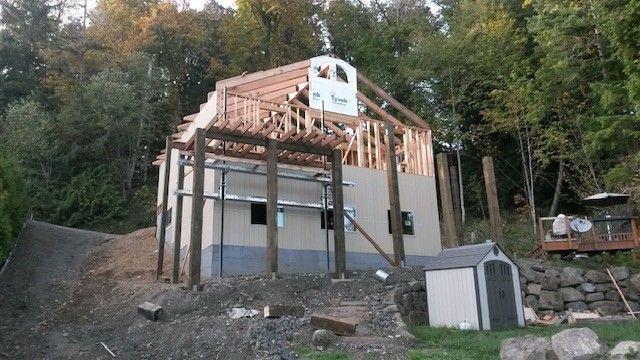 A house is being built on a hill in the woods.