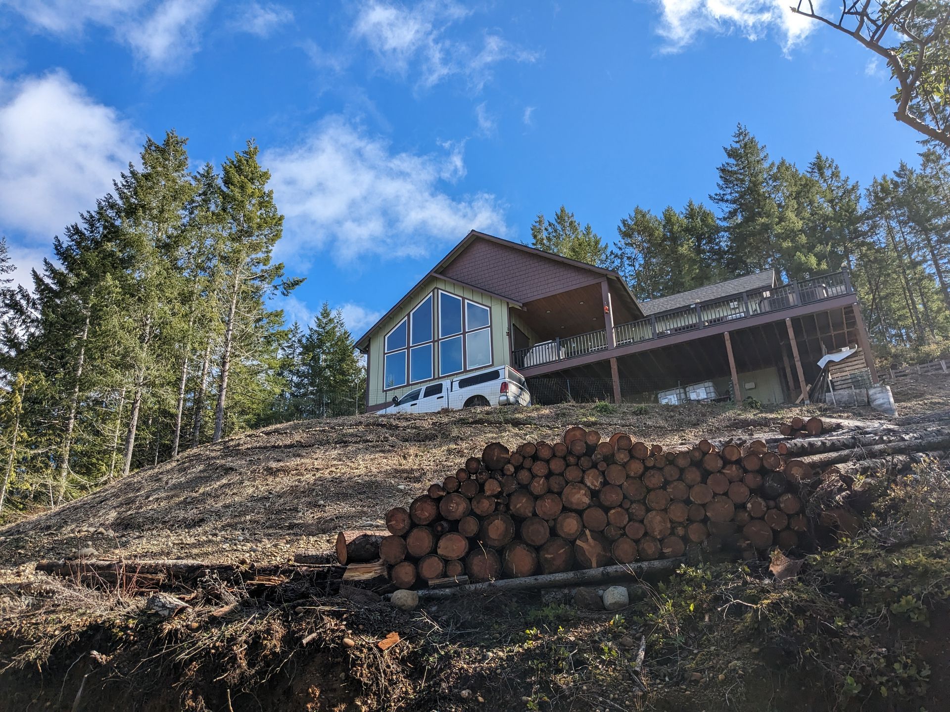 A house on a hill with a pile of logs in front of it