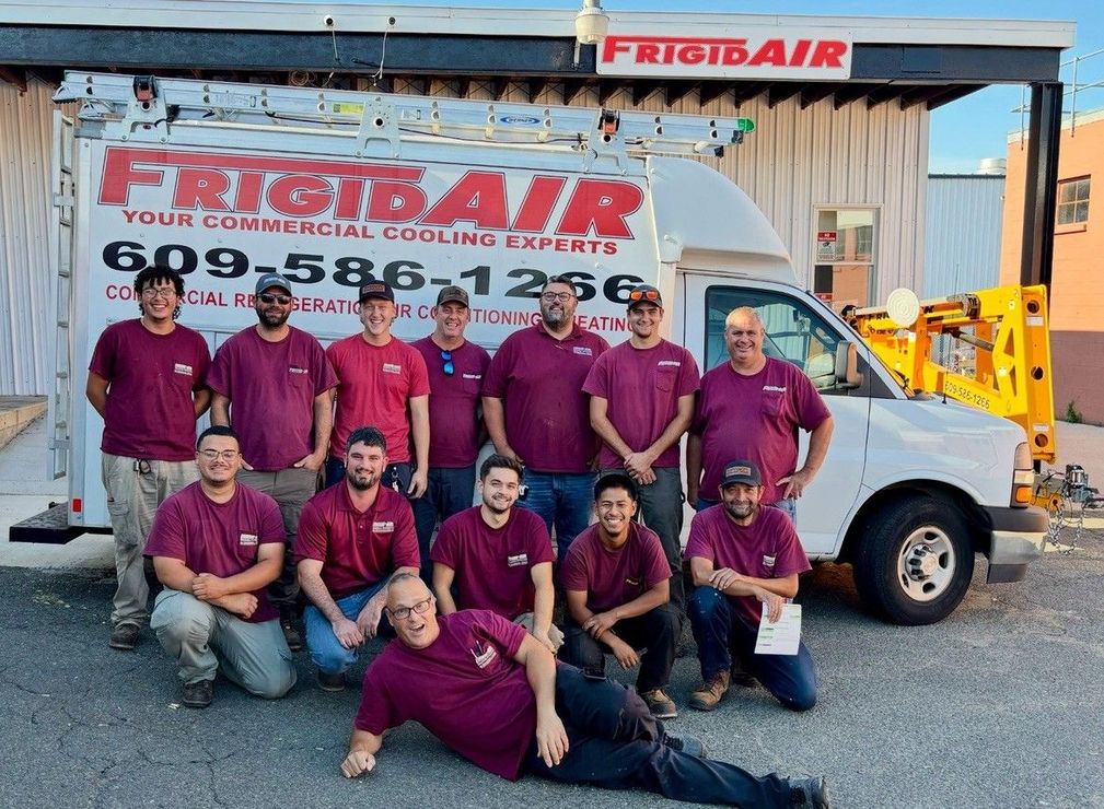 Brick building with a white steeple topped by a teal spire against a light blue sky.