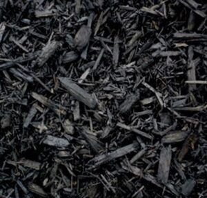 A close-up view of black wood mulch, consisting of dark, irregularly shaped wood chips and small bark fragments.