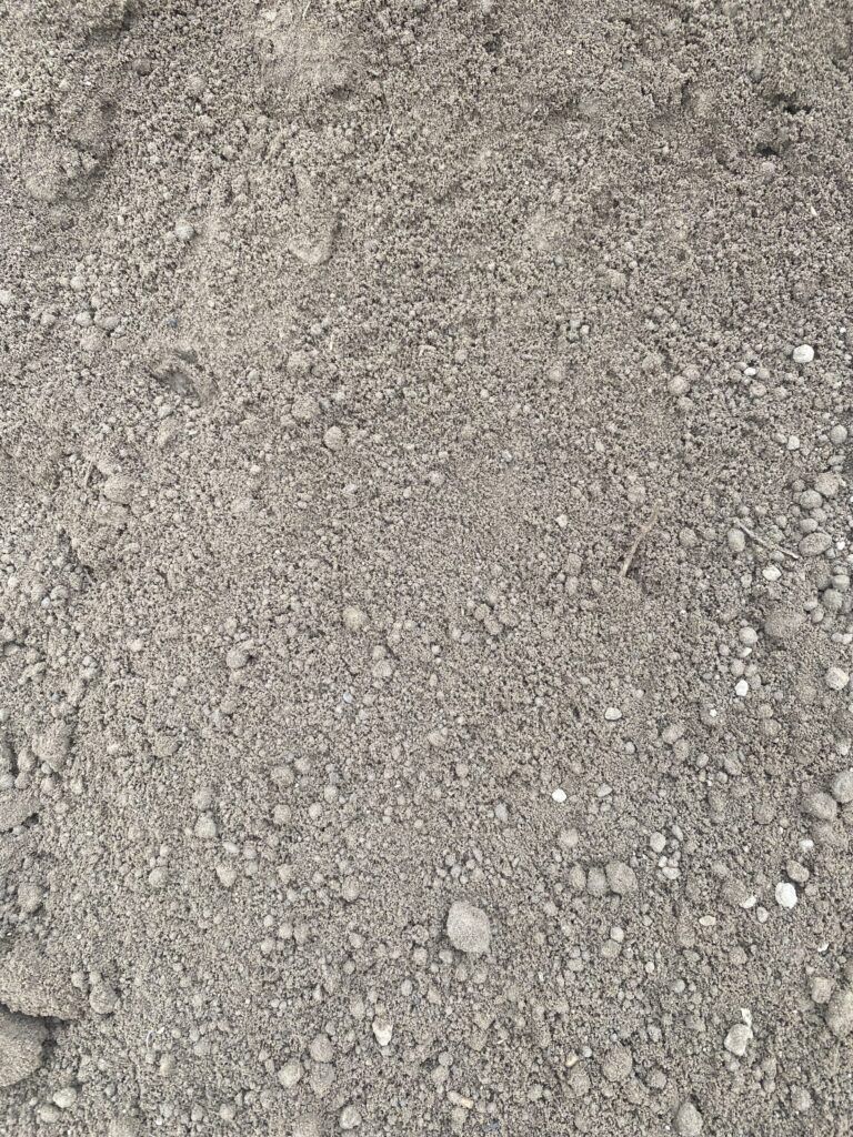 A close-up view of coarse, gray gravel and dirt scattered on the ground.