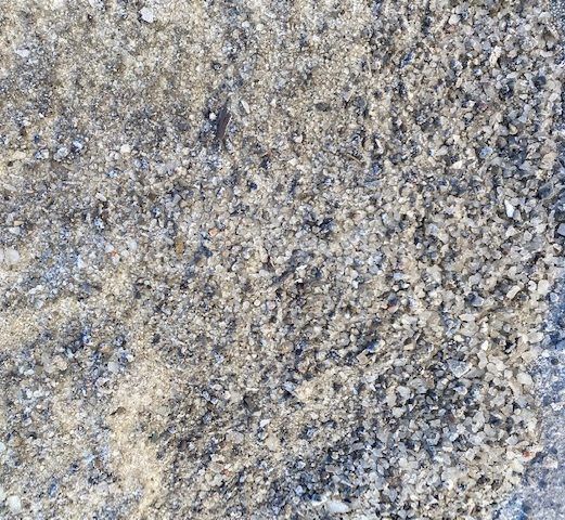 Close-up view of textured, grey and beige granular gravel or stone surface.