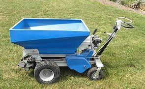 A blue walk-behind power barrow or motorized cart with a hopper, standing on a green grass lawn.