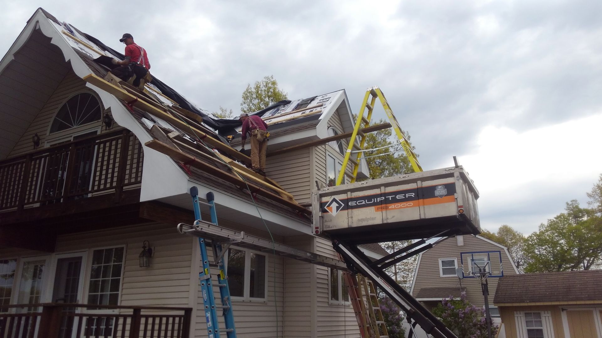 Beige house with brown roof and white trim, featuring a large arched window and a rectangular window.