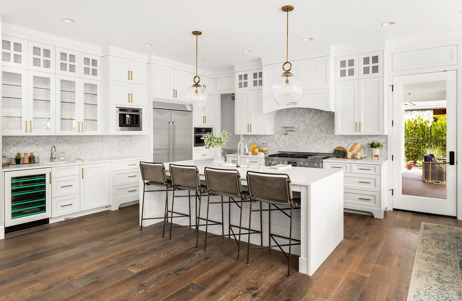 White kitchen with island, stainless steel appliances, and wood floors.