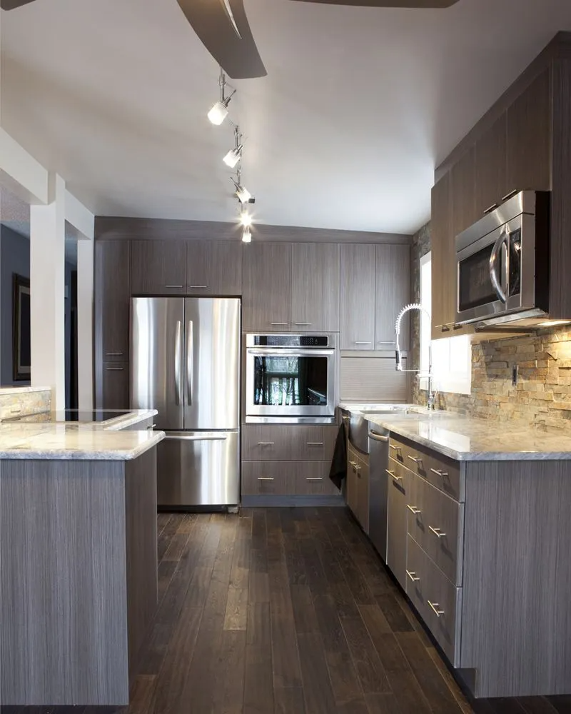 Modern kitchen with stainless steel appliances, gray cabinets, and dark wood floors.