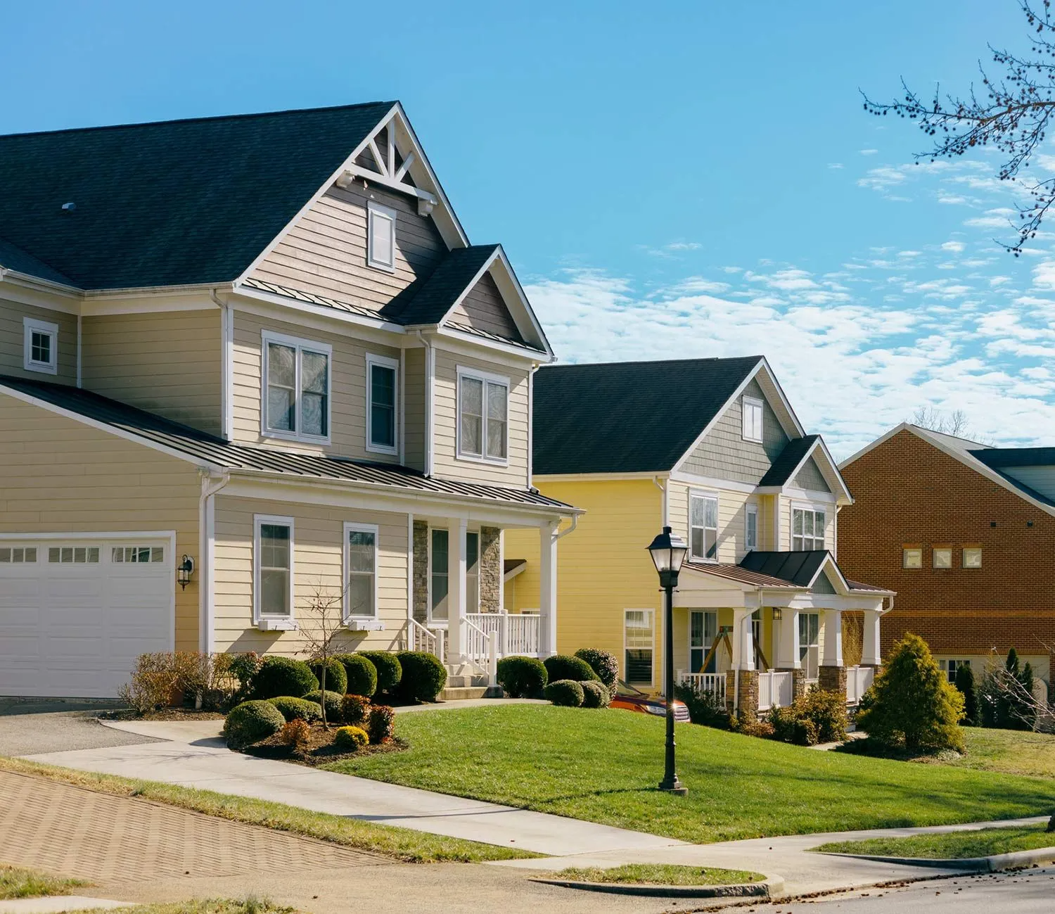 Row of houses on a sunny day with green lawns and blue sky.
