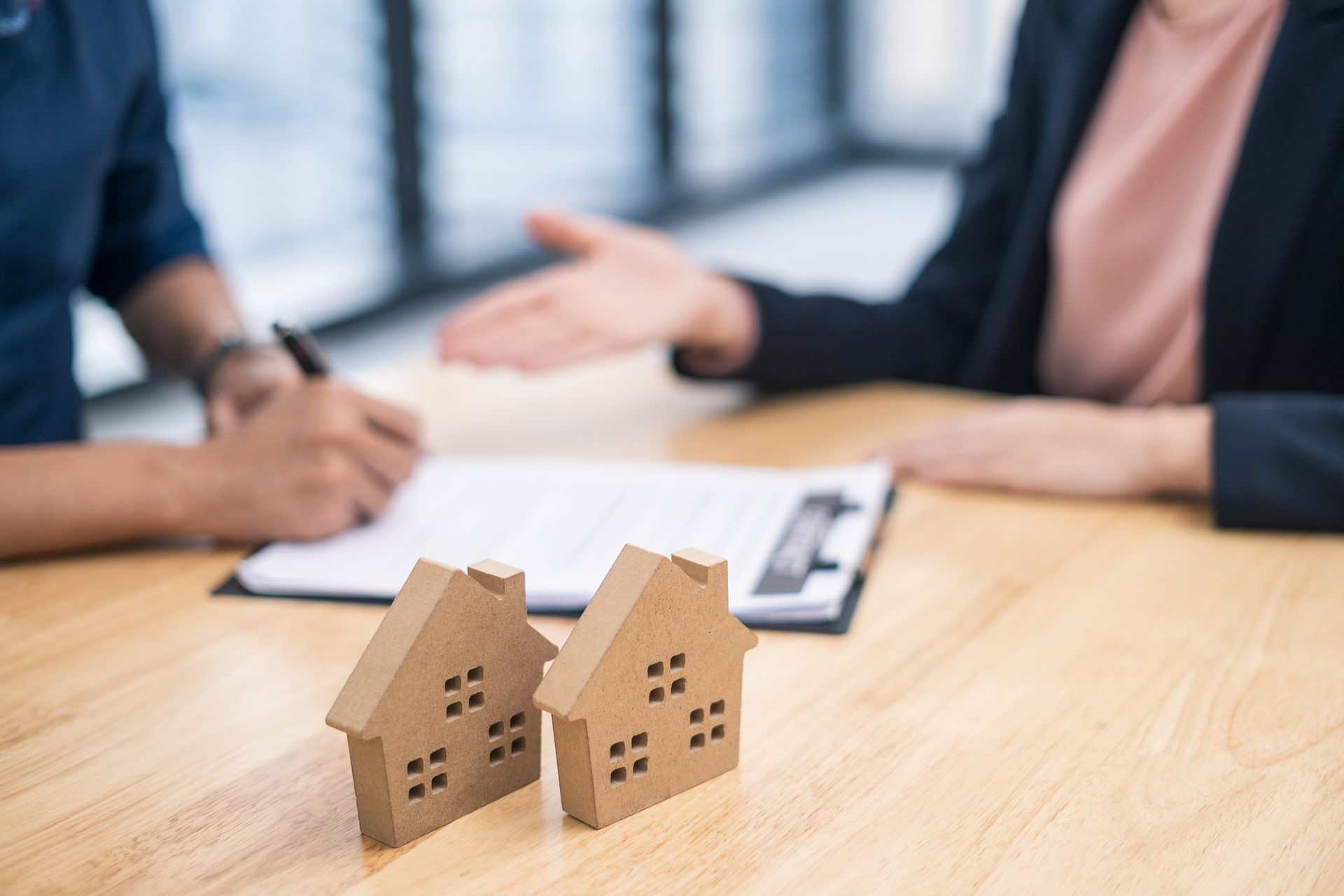 A man and a woman are sitting at a table with two wooden houses on it.
