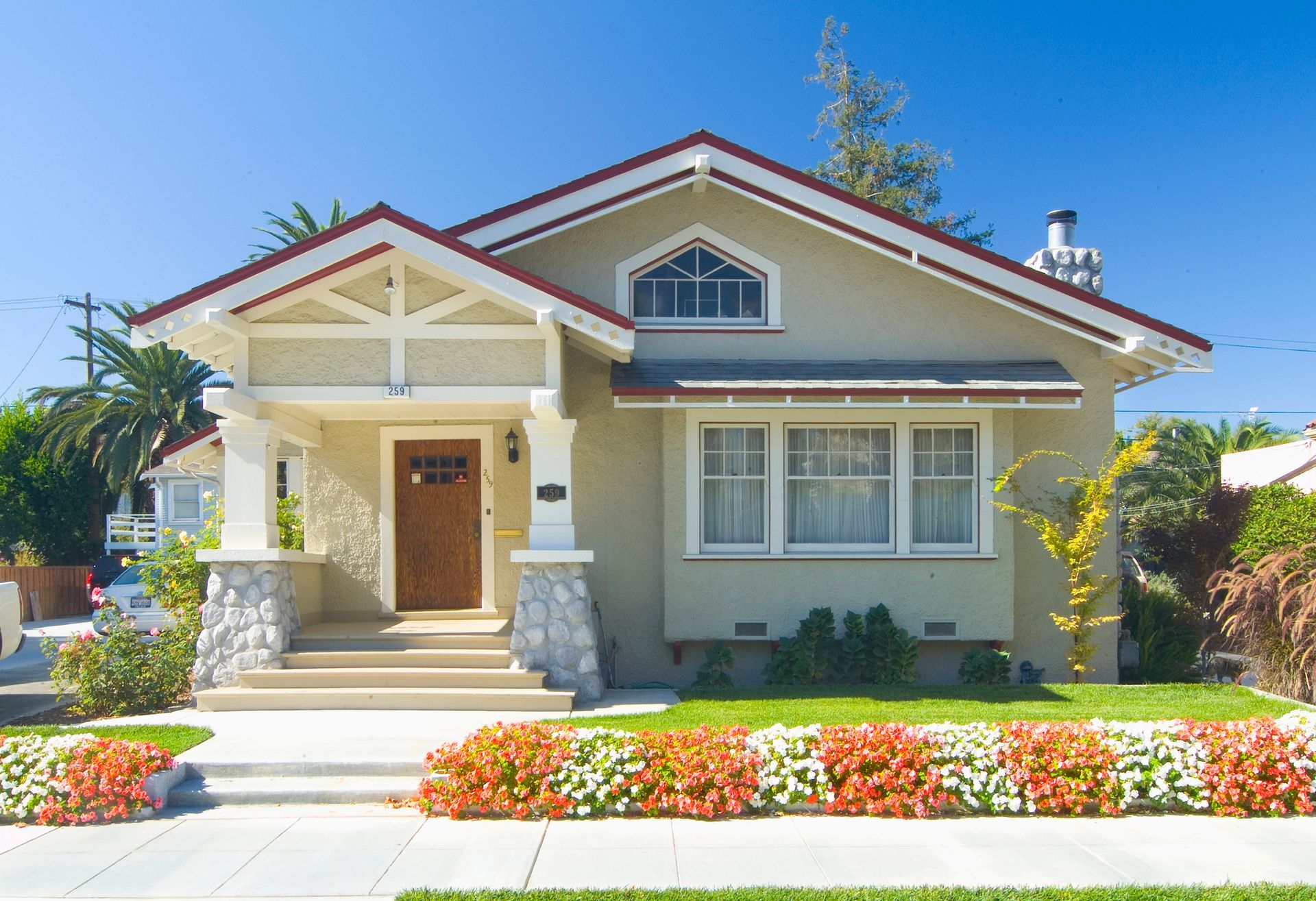 A house with a red roof and flowers in front of it