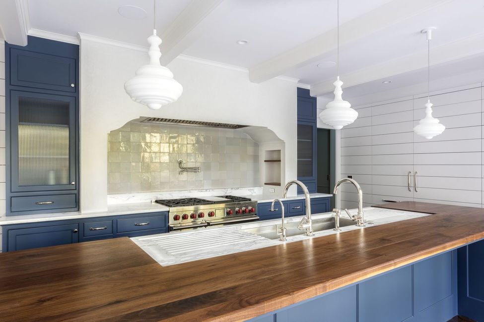 A kitchen with blue cabinets and a wooden counter top.