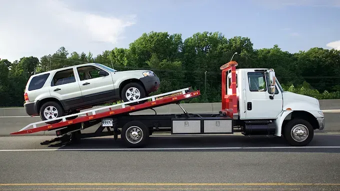 A tow truck is carrying a suv on its back.