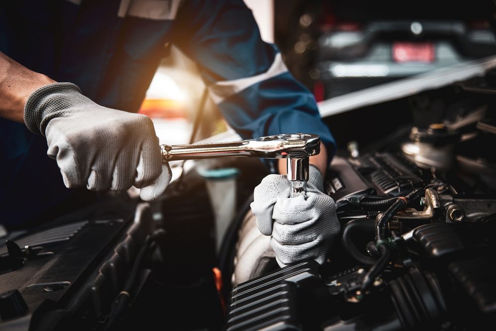 A mechanic is working on a car engine with a wrench.