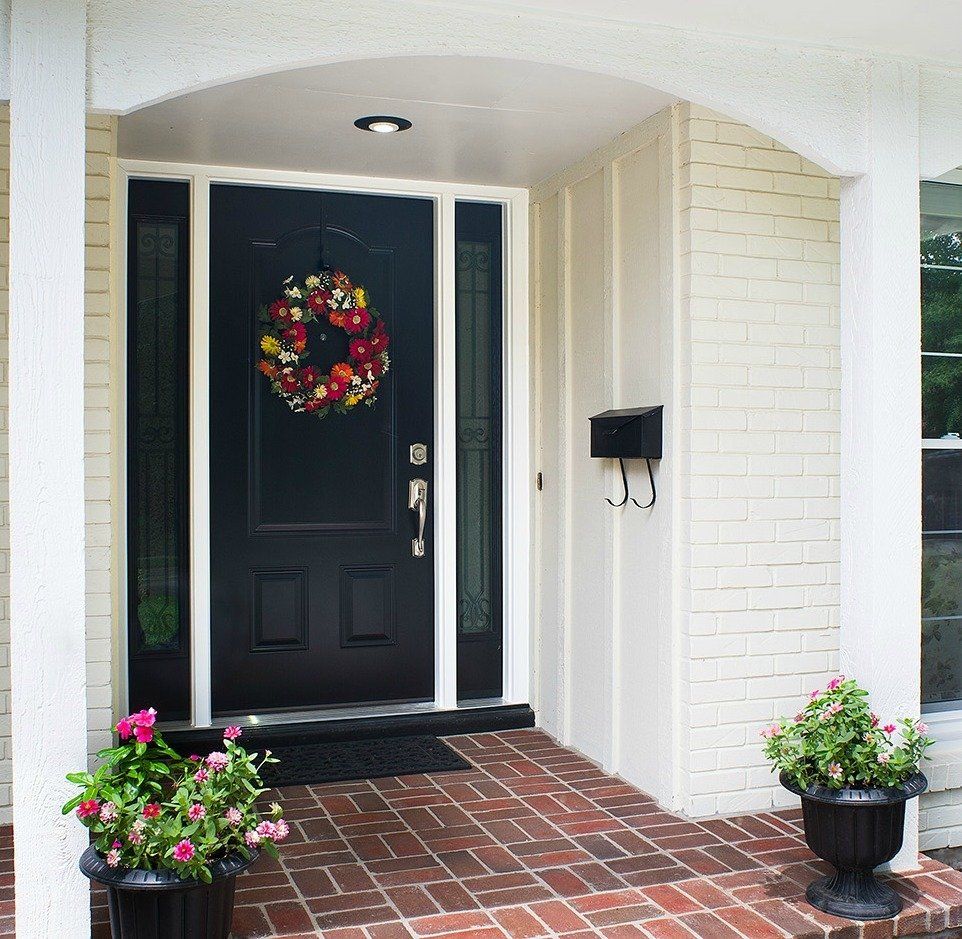 black entry door to home with decorative wreath