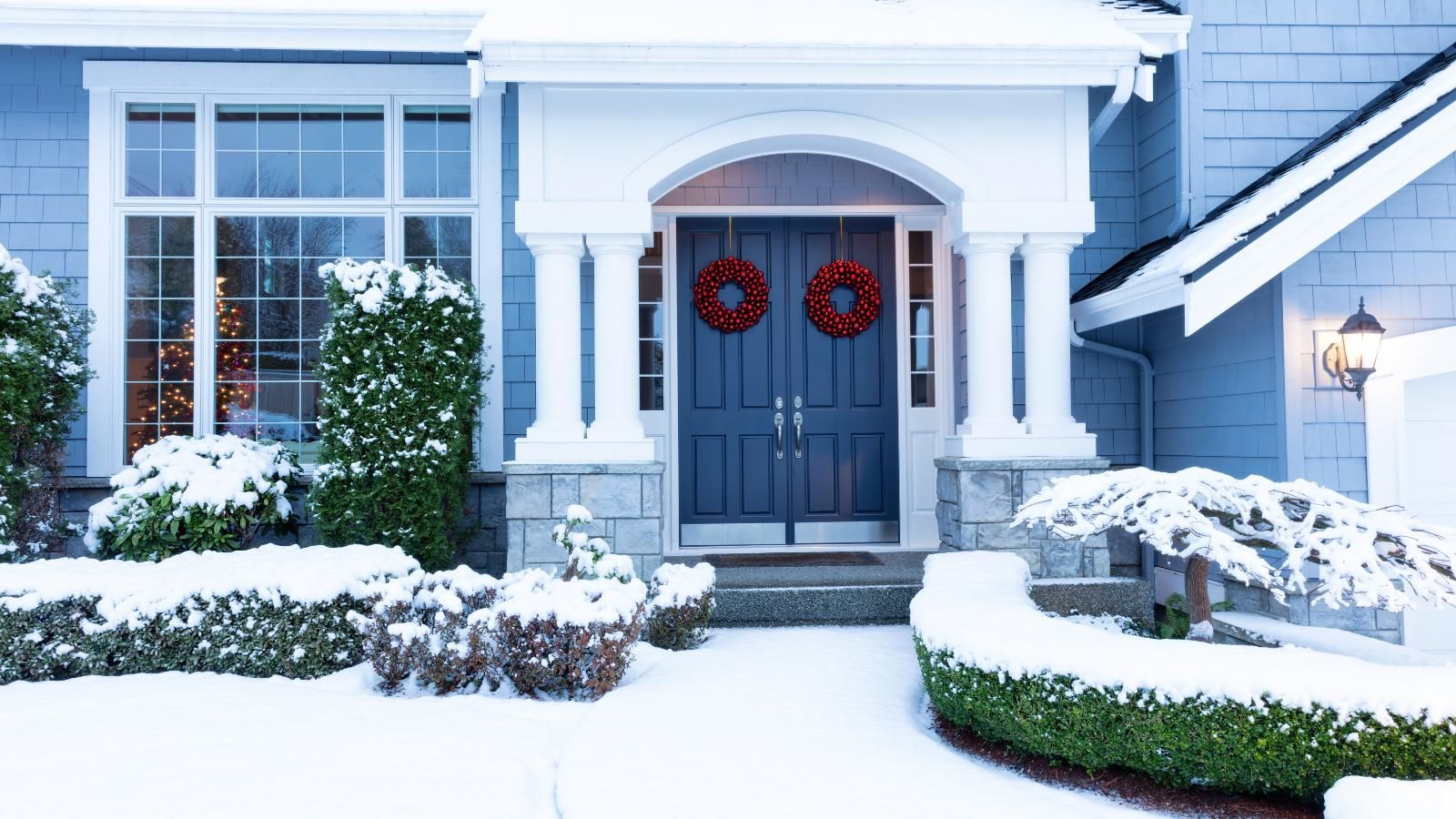 A house with snow on the ground and door closed against the cold. 