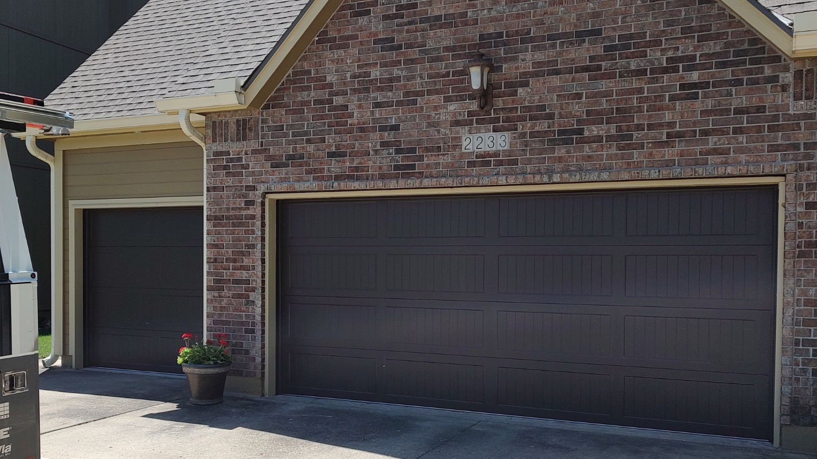 A brick house with two garage doors and a potted plant