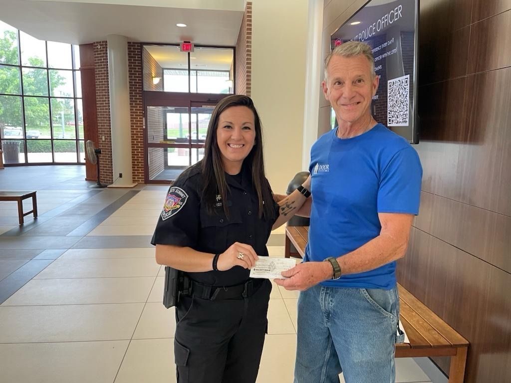 Terry Gochnauer is giving a police officer a check in a lobby.