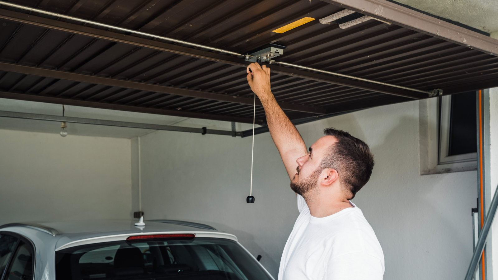 A man is inspecting a garage door spring.