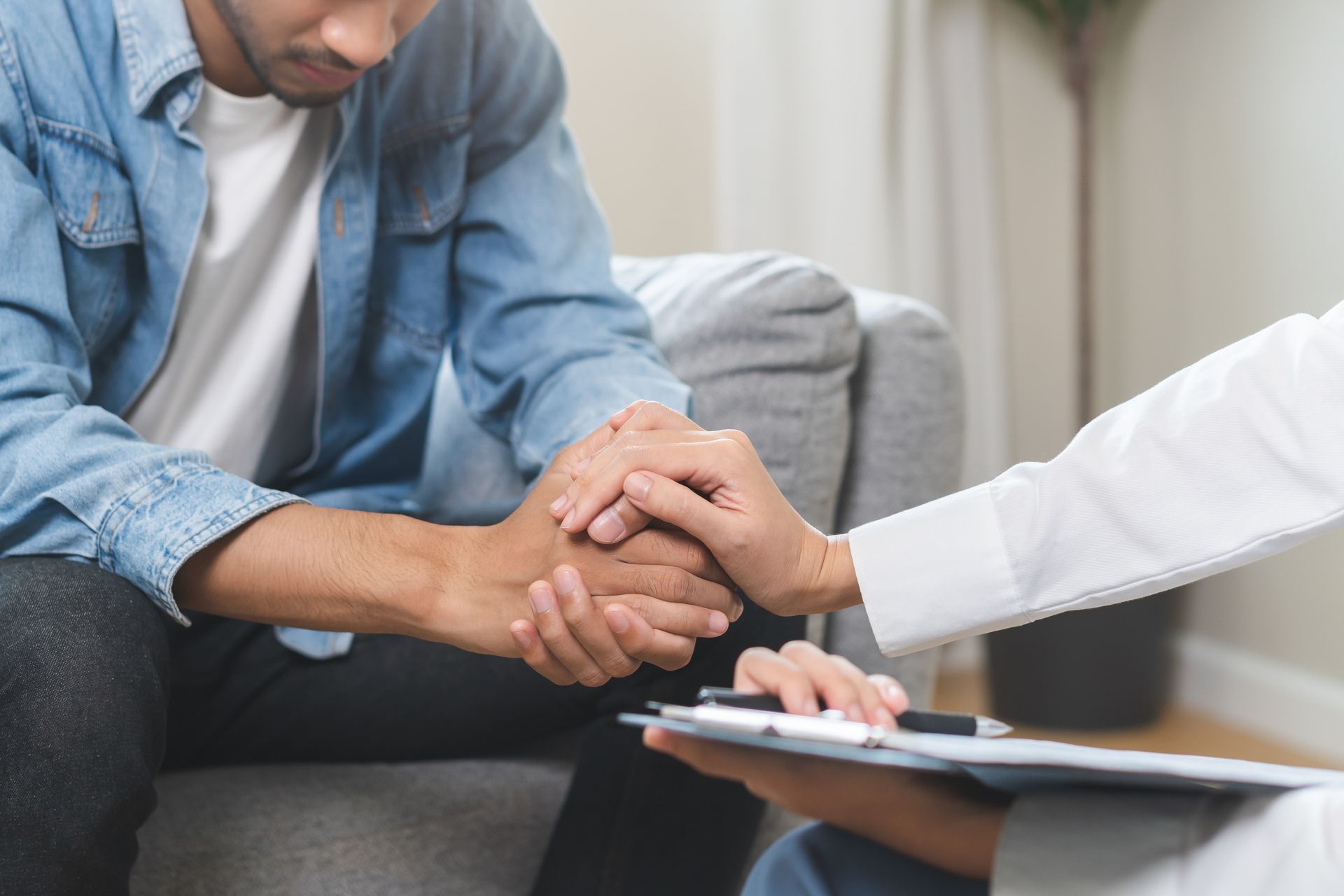 A person receives comfort from a healthcare provider. The provider's hand gently rests on the patient's.