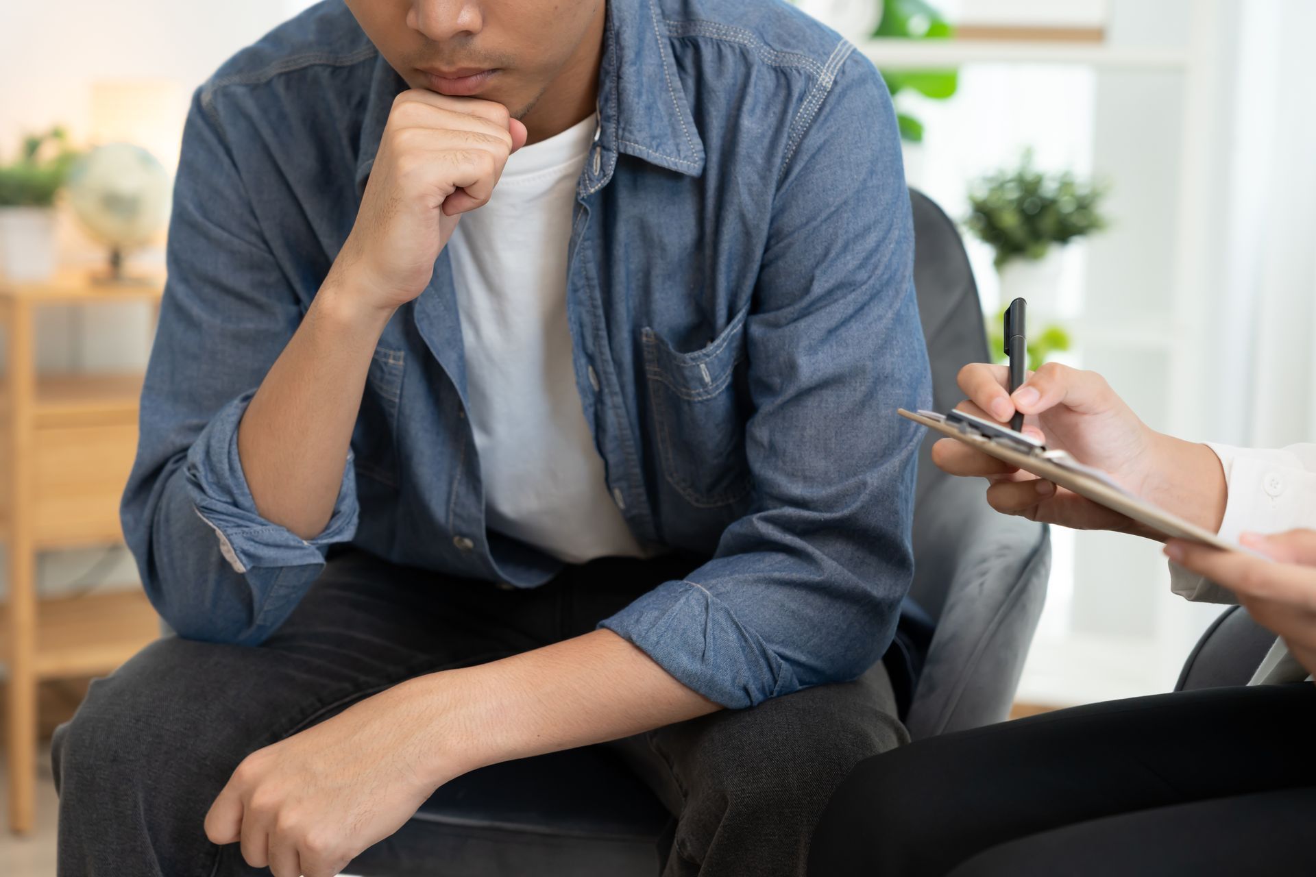 Man in therapy session; holding chin, listening to notes being taken. Man in therapy session; holding chin, listening to notes being taken.