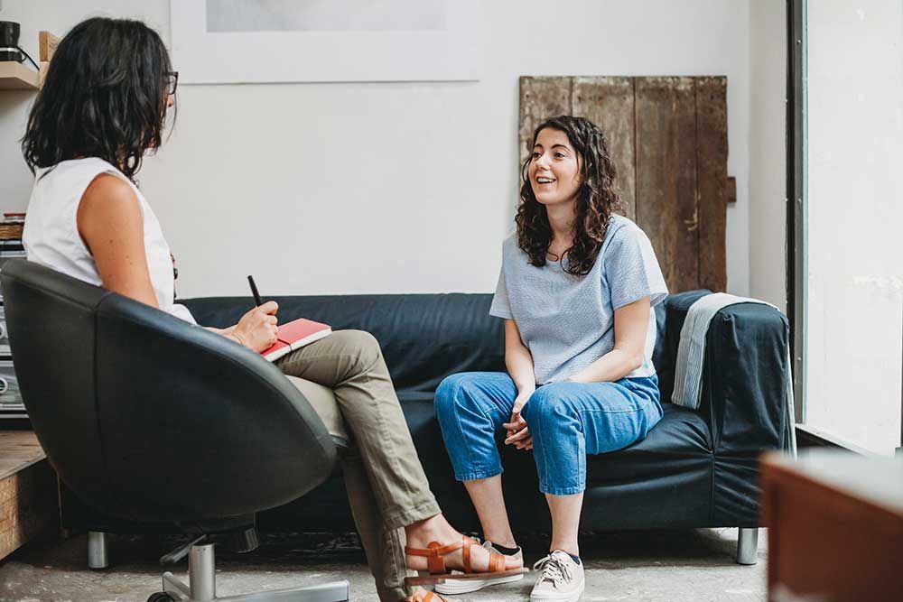 Woman smiles while talking to therapist in an office. Woman smiles while talking to therapist in an office.