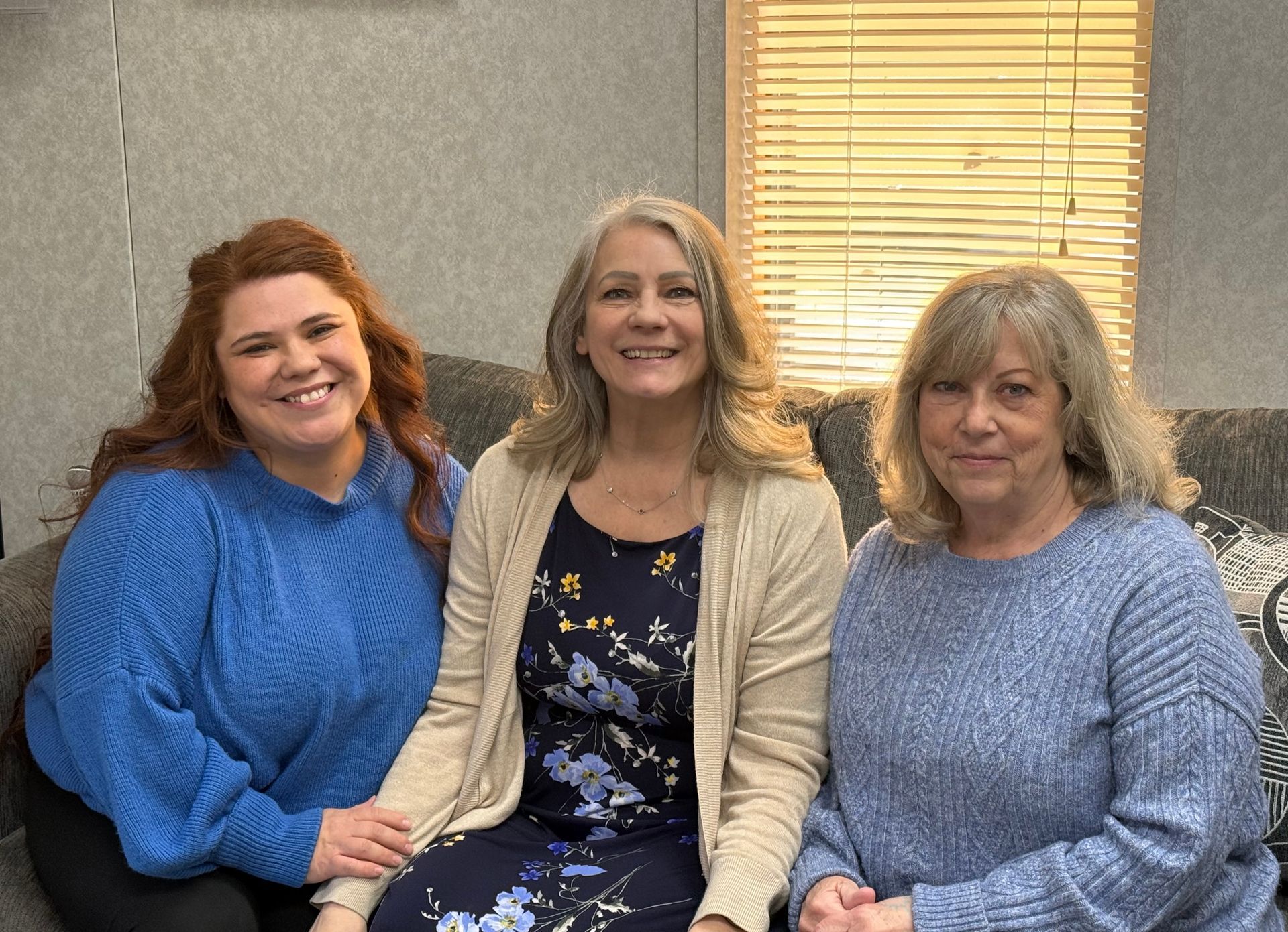 Couple signing documents with a consultant at a desk; smiles, indoors, laptop. Couple signing documents with a consultant at a desk; smiles, indoors, laptop.