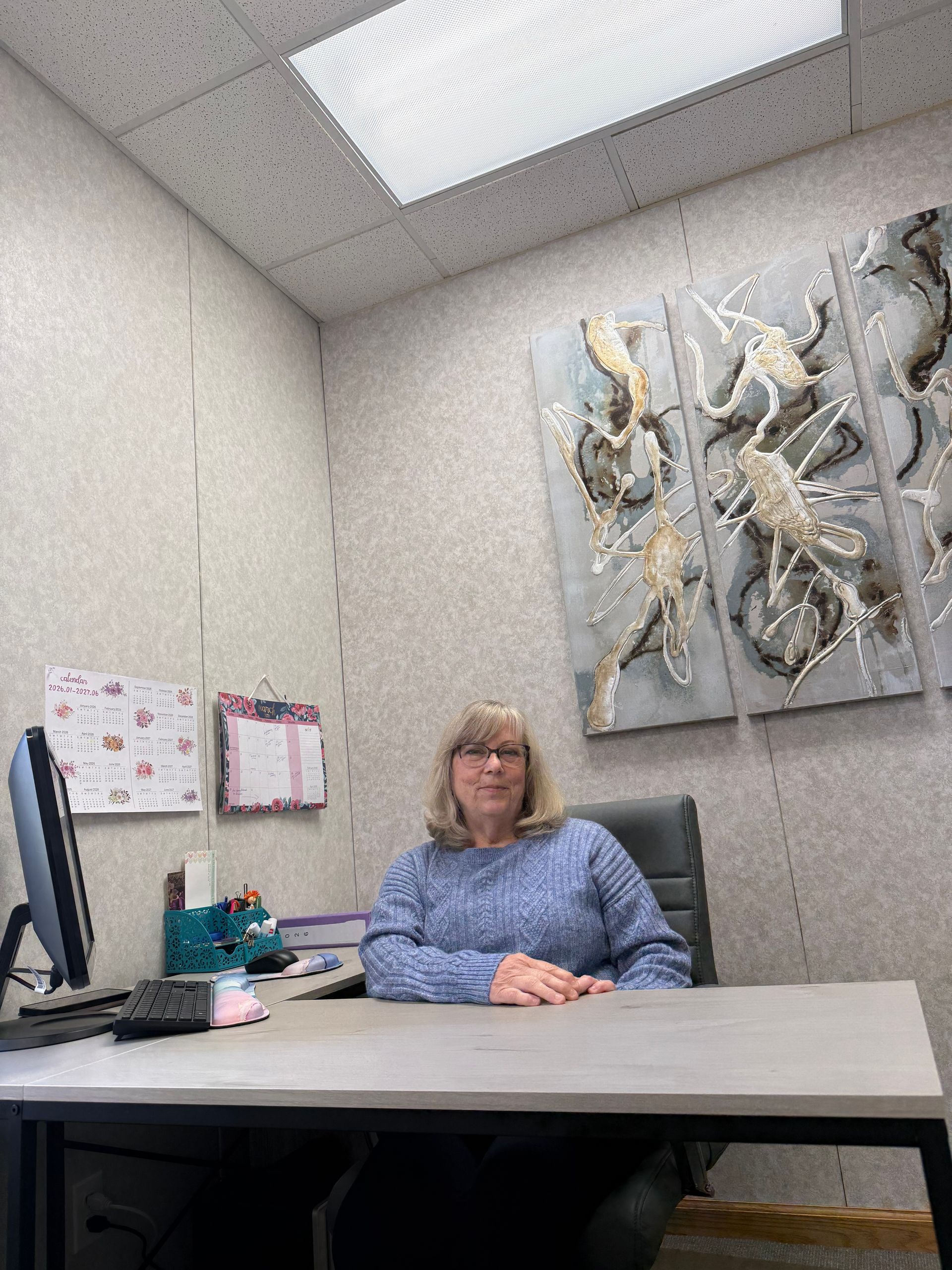 Woman in red shirt smiles, petting a brown dog indoors.