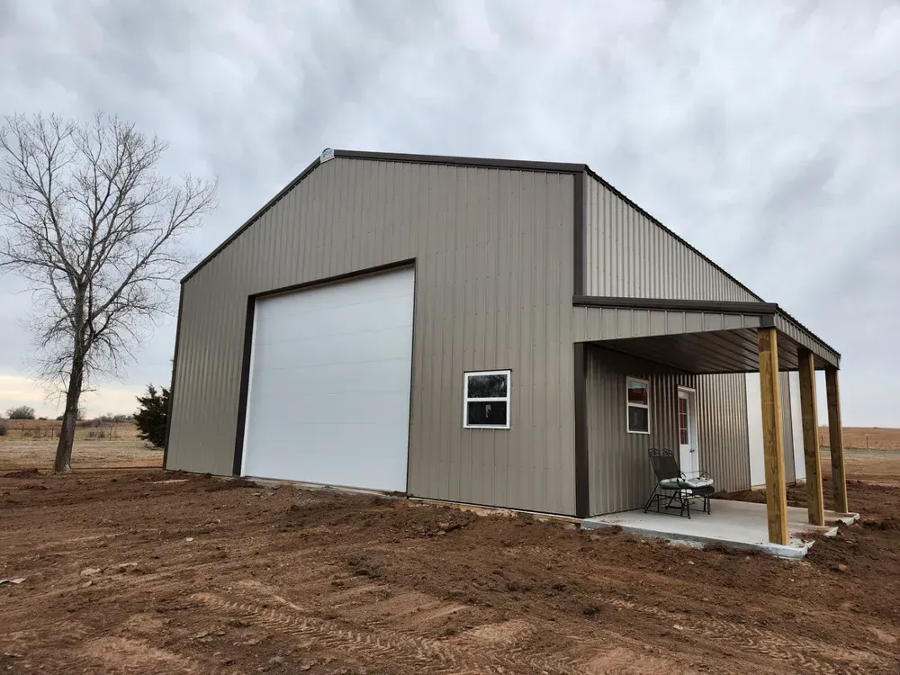 A large metal building with a large garage door and a porch.