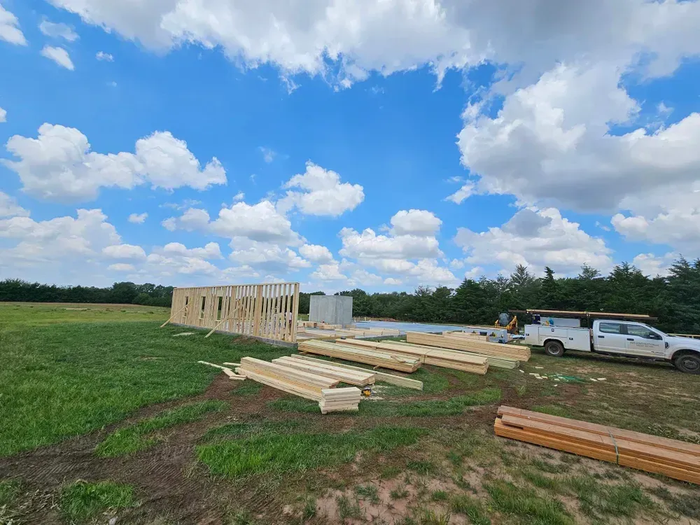 A truck is parked in a field next to a building under construction.