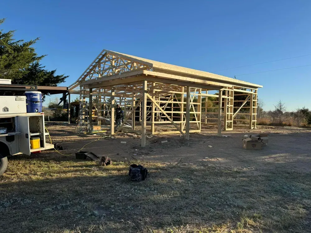 A large wooden structure is being built in a field.