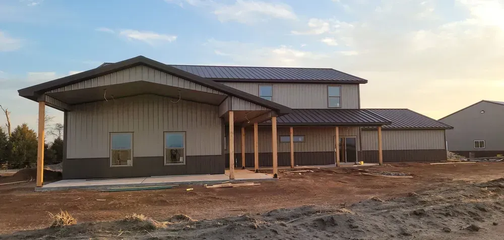 A large house is being built in the middle of a dirt field.