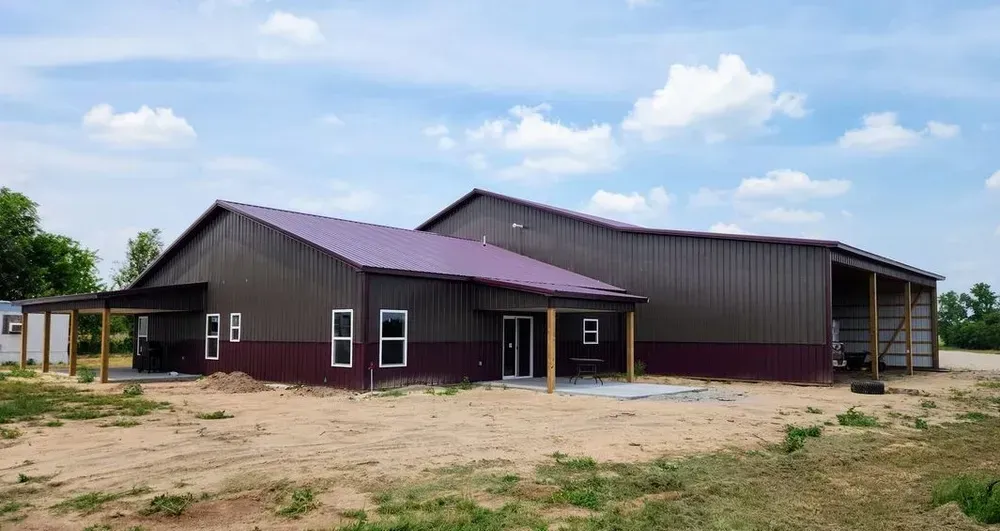 A large building with a purple roof is sitting on top of a dirt field.