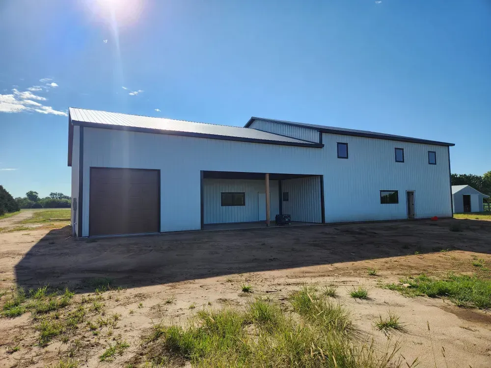 A large white building is sitting in the middle of a dirt field.