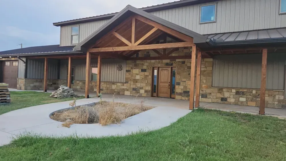 A large house with a wooden porch and a stone wall.