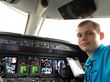 A man in a blue shirt is sitting in the cockpit of an airplane.