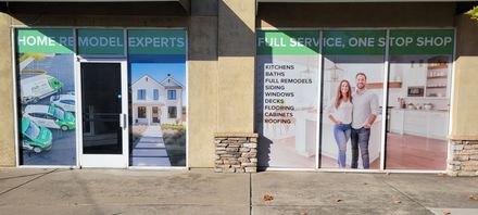 Exterior storefront with windows displaying home remodeling services; building entrance.