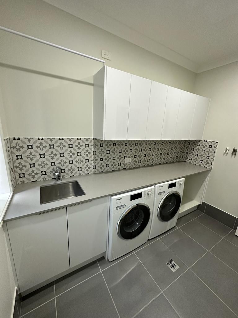 A laundry room with a washer and dryer and a sink.