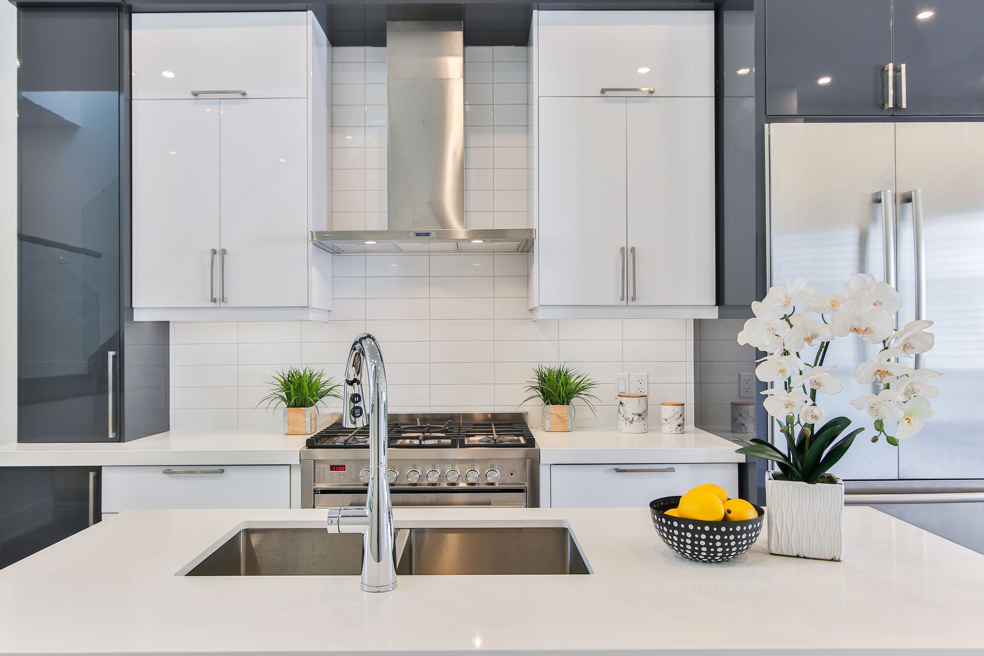 A kitchen with white cabinets , stainless steel appliances , a sink and a stove.