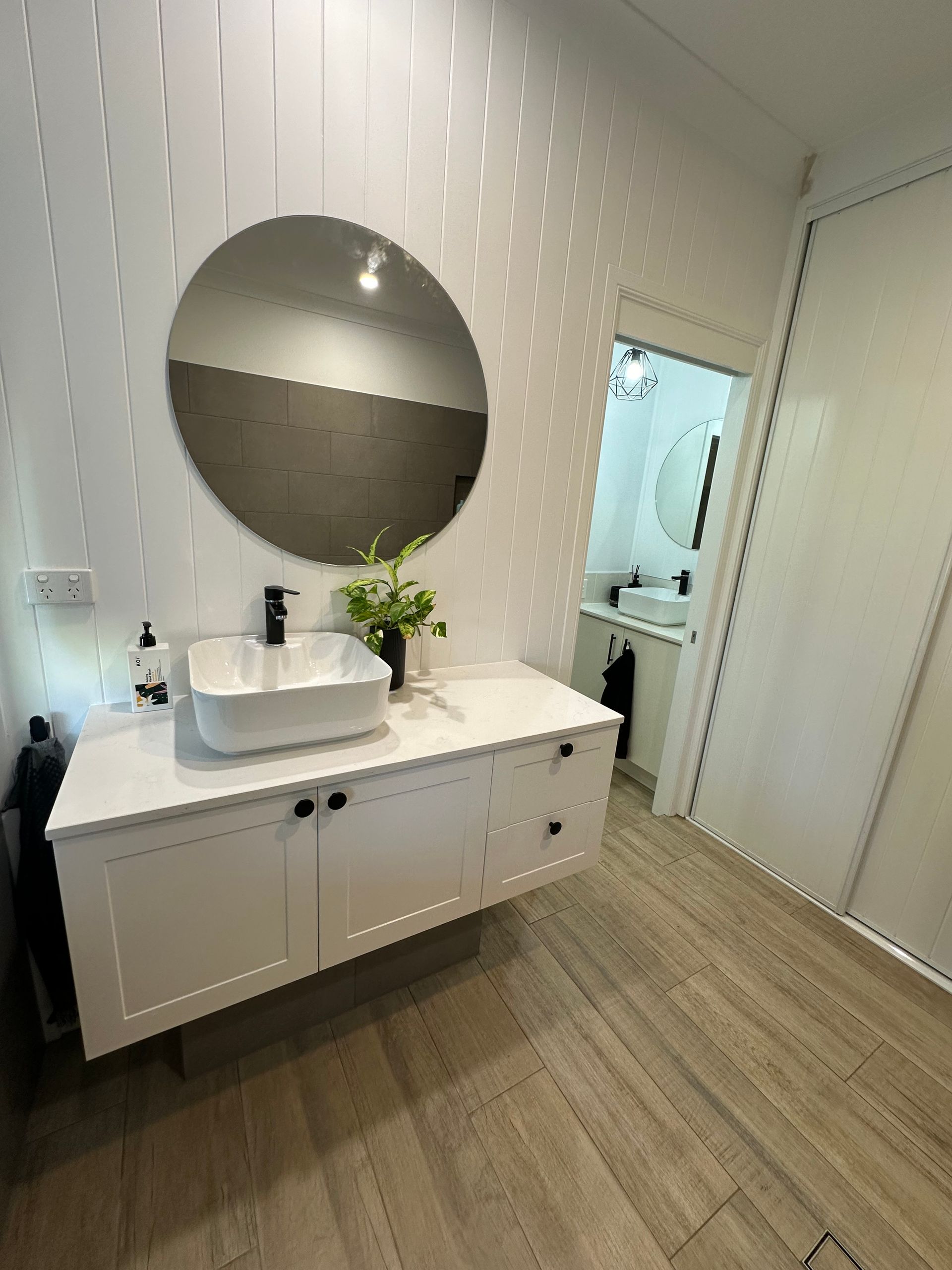 A bathroom with a sliding glass shower door and a robe hanging on the wall.