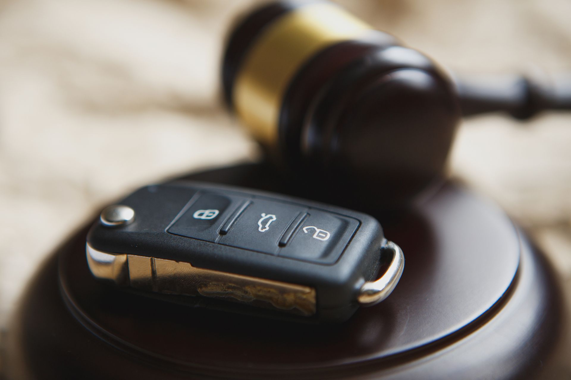 Close-up Of Gavel And Car Key On Sounding Block Against Grey Background