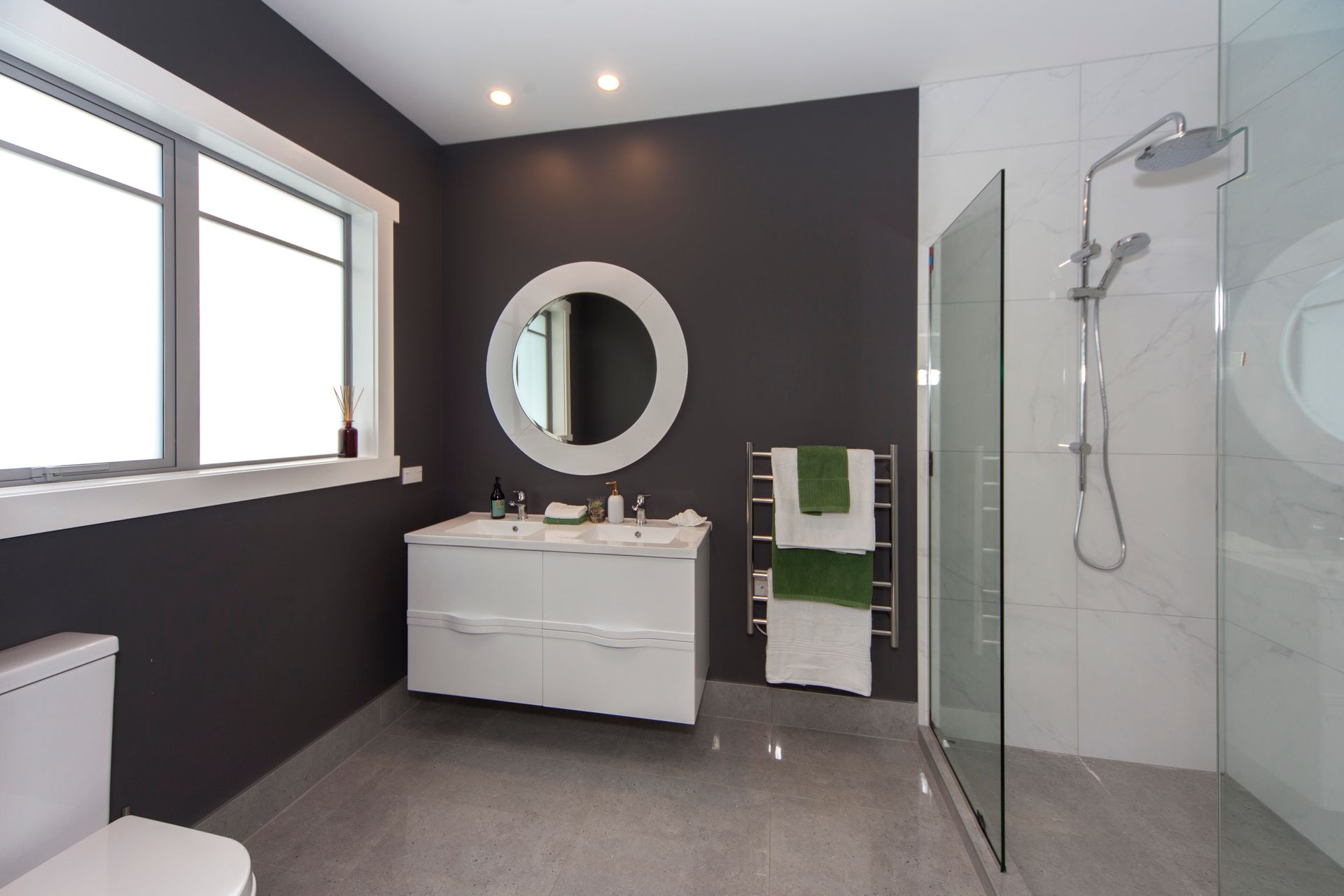 Modern bathroom with white vanity, gray walls, and walk-in shower.