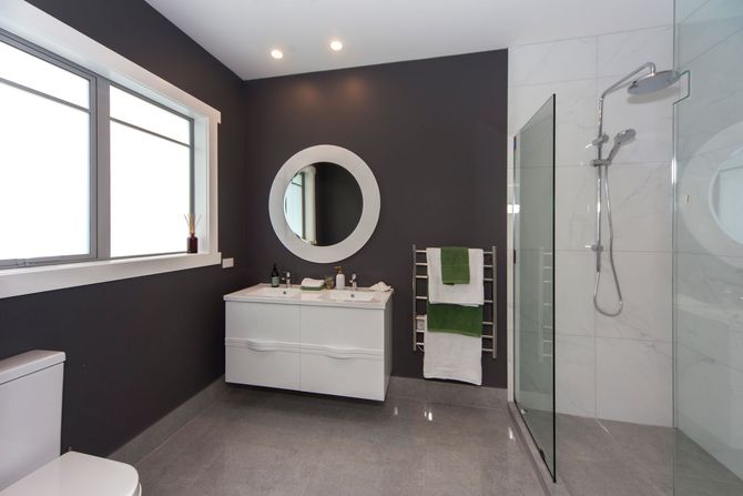 Modern bathroom with white vanity, gray walls, and walk-in shower.