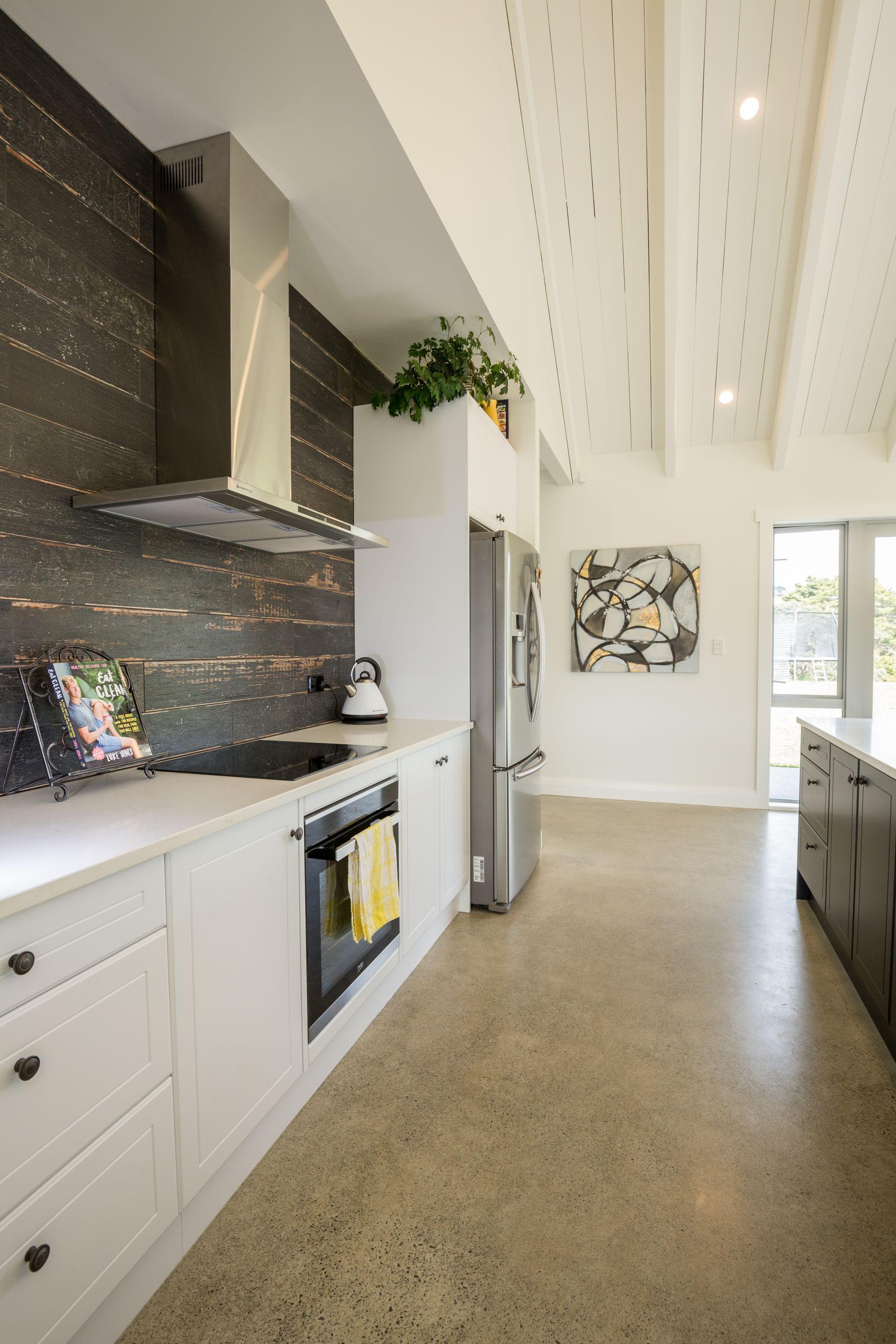 Modern kitchen with white cabinets, stainless steel appliances, and dark backsplash.