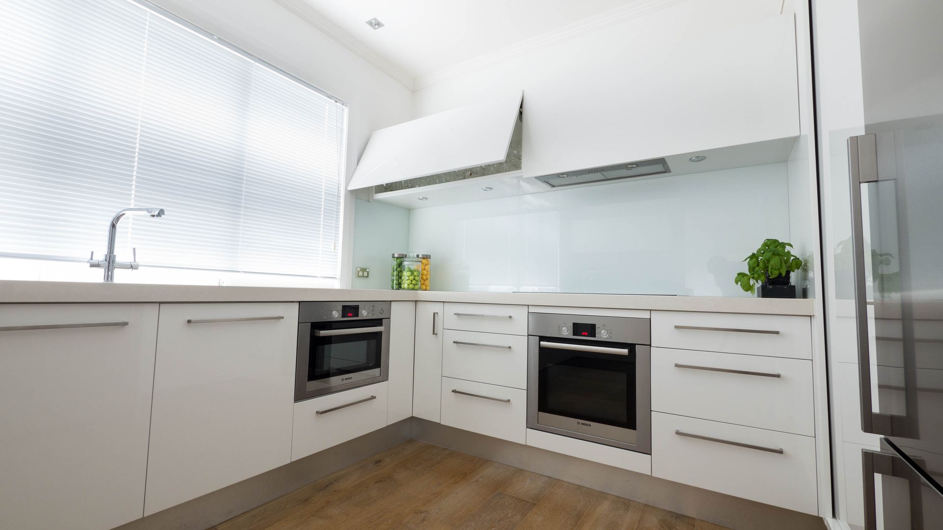White kitchen with stainless steel appliances and light wood floors.