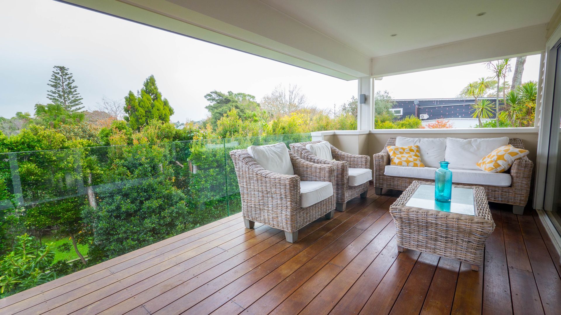 Covered porch with wooden slats, overlooking backyard with grass and fence.