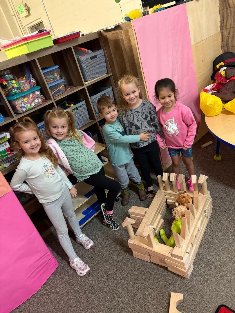 Group of people in purple and black Halloween-themed outfits pose in front of a balloon arch that spells