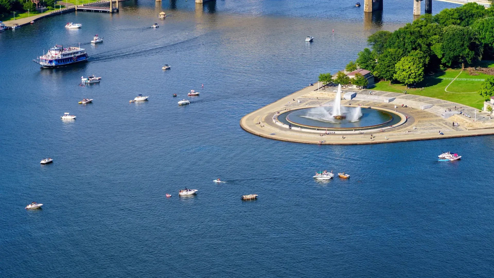 An aerial view of a lake with boats and a fountain in the middle.